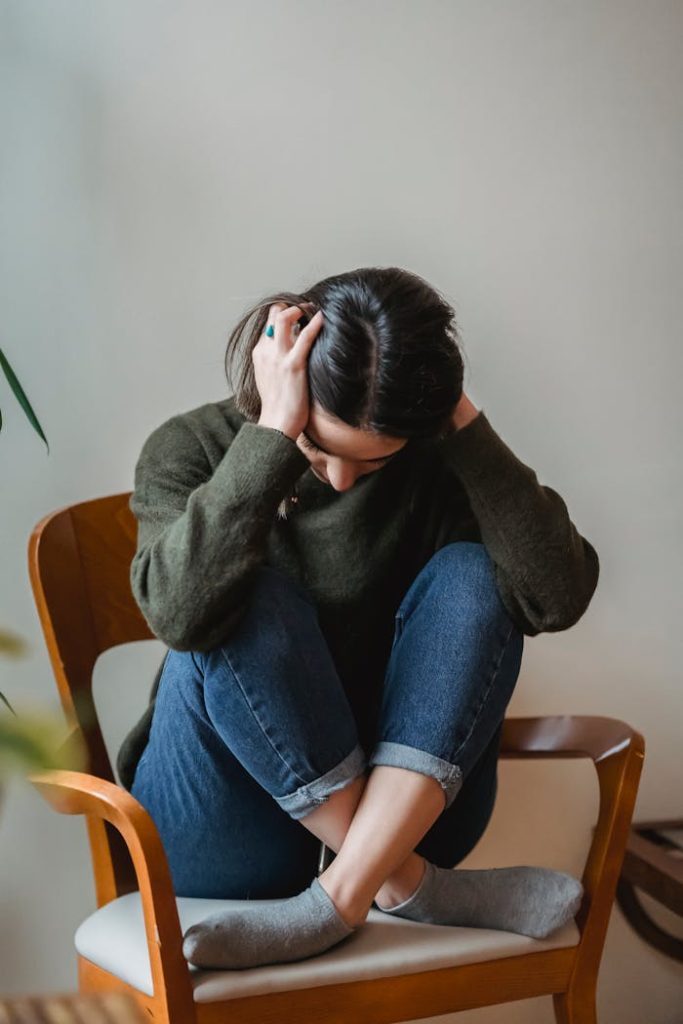 pexels-photo-6382633 Anxious young woman cover wing ears with hands sitting on chair